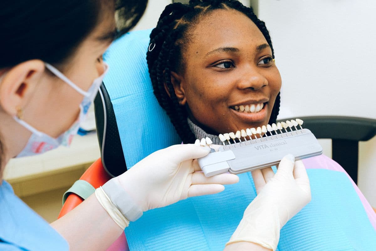 Dentist matching tooth shade with a VITA guide for restorative crown design